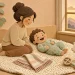 Мама на пледе играет с малышом, рядом платок и игрушечная коза
